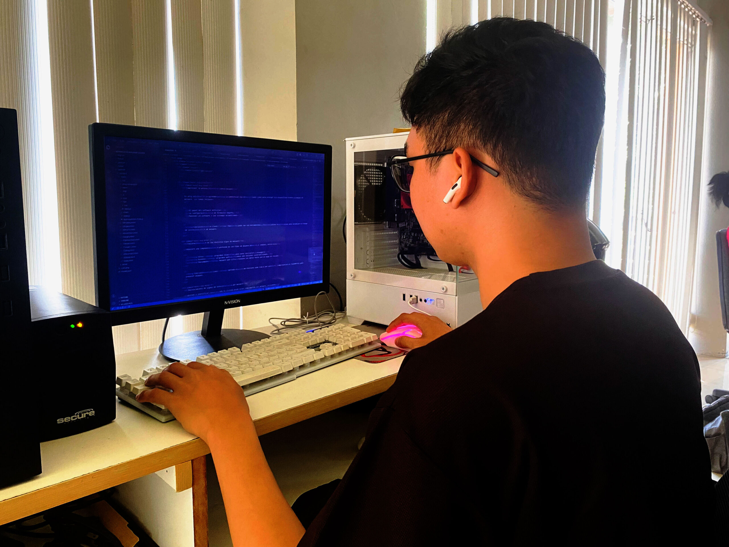 Individual working on programming tasks at a desk using a computer.