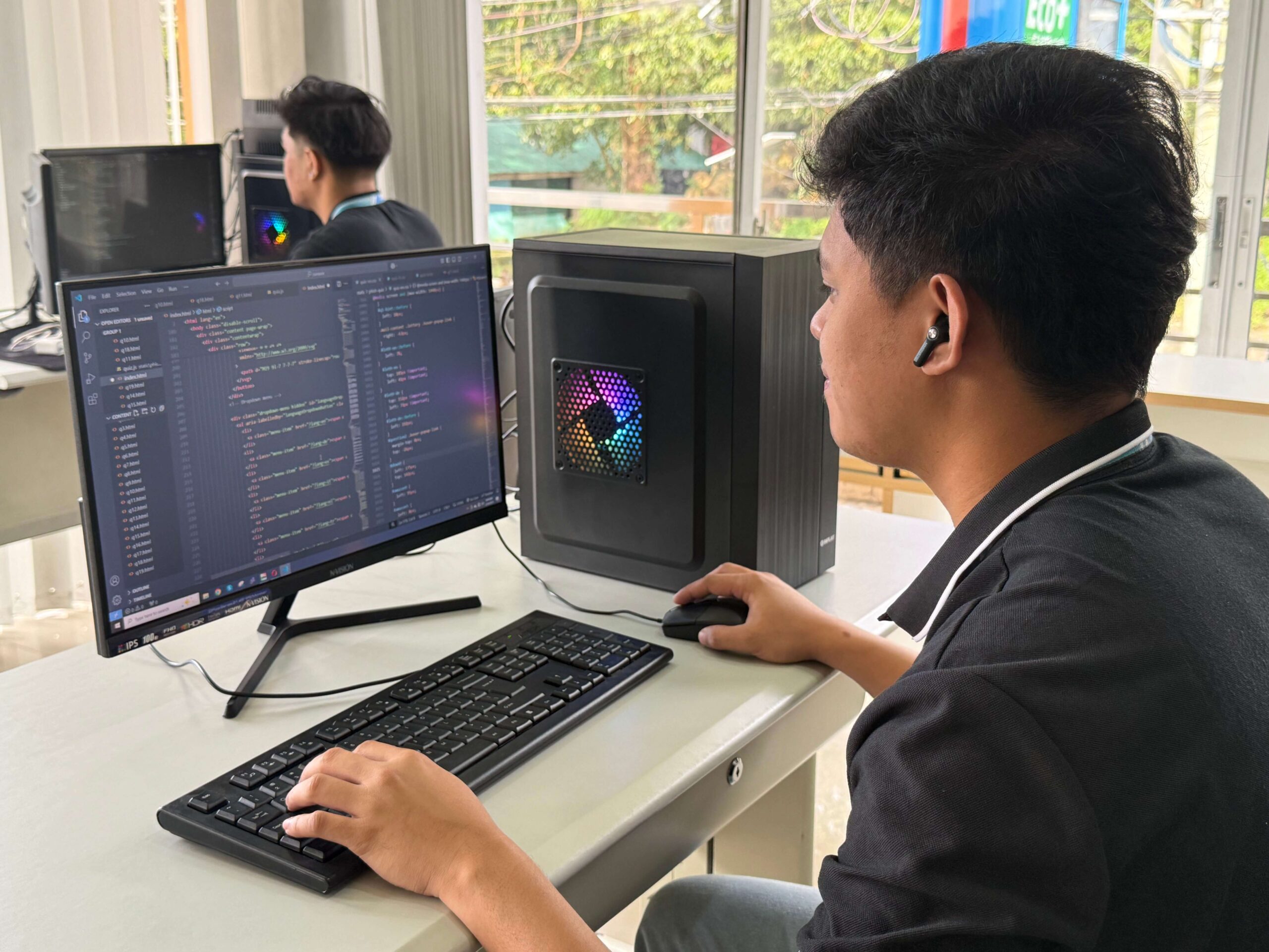 Tech workstation with desktop computer, keyboard, and coding interface for software development.